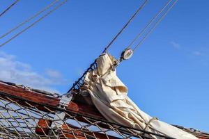 Sailing ship mast against the blue sky on some sailing boats with rigging details. photo