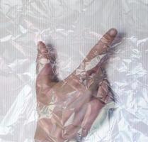 Hand of a young female wrapped in plastic film showing different gestures photo