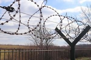 Barbed wire against a cloudy sky on a big fence at a border. photo