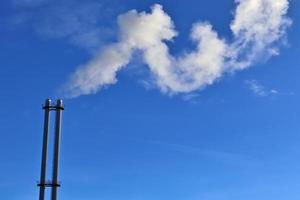 contaminación industrial de las chimeneas de fábrica en un cielo azul profundo foto