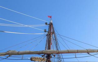 Sailing ship mast against the blue sky on some sailing boats with rigging details. photo