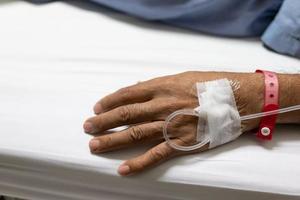 Close up the patient's hands and arms are giving the saline solution on bed with copy space. photo