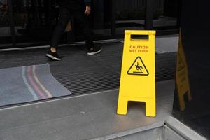 Yellow Caution slippery wet floor sign on the wet ground photo