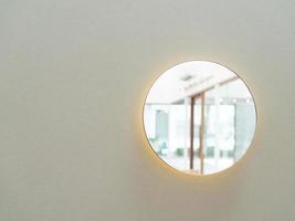 Small round looking glass mirror on wall background. Reflected round mirror photo