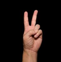 The man's hand that holds two fingers is a V sign, meaning victory. Or still means peace and contempt for challenges on black background photo