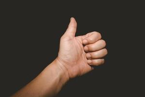 The man's hand that thumbs up is a symbol of admiration on black background photo