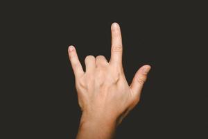 la mano del hombre que sostiene su dedo muestra el símbolo te amo en un fondo negro. foto
