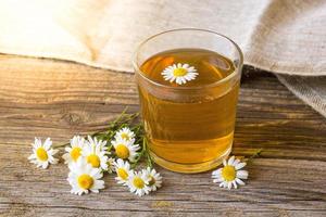 taza de té con flores de manzanilla sobre fondo de madera rústica foto