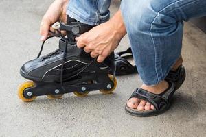 Closeup of man guy putting on roller skates outdoor photo