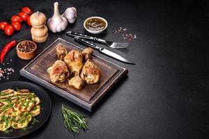 Three chicken legs grilled with spices and herbs on a wooden cutting board photo