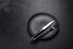 Black plate on a black background. Flat lay, top view, copy space photo