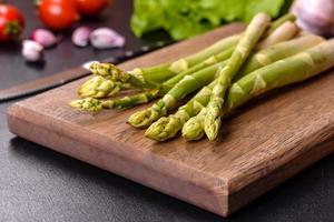 A bunch of branches of fresh green raw asparagus on a wooden cutting board photo