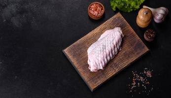 Fresh raw turkey wing with spices and herbs on a wooden cutting board photo