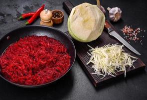 Chopped beetroot in a pan as well as spices and herbs on a wooden cutting board photo