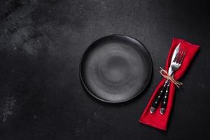 Christmas table setting with empty black ceramic plate, fir tree and black accessories photo