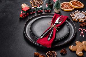 Christmas table setting with empty black ceramic plate, fir tree and black accessories photo