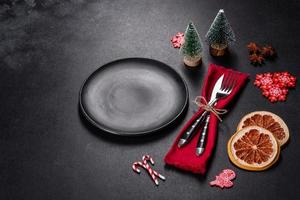 Christmas table setting with empty black ceramic plate, fir tree and black accessories photo