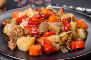 Vegetable stew or ratatouille with eggplant, tomatoes, sweet and hot peppers, onions, carrots and spices in plate photo