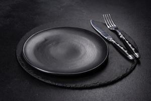 Black plate on a black background. Flat lay, top view, copy space photo