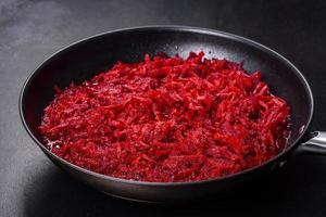 Chopped beetroot in a pan as well as spices and herbs on a wooden cutting board photo