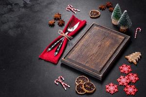 Christmas table setting with empty black ceramic plate, fir tree and black accessories photo