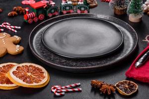 Christmas table setting with empty black ceramic plate, fir tree and black accessories photo