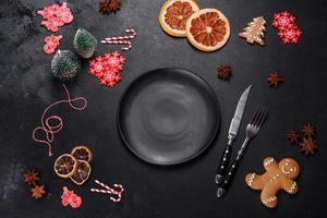 Christmas table setting with empty black ceramic plate, fir tree and black accessories photo