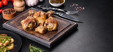 Three chicken legs grilled with spices and herbs on a wooden cutting board photo