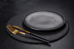 Black plate on a black background. Flat lay, top view, copy space photo