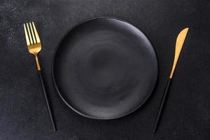 Black plate on a black background. Flat lay, top view, copy space photo