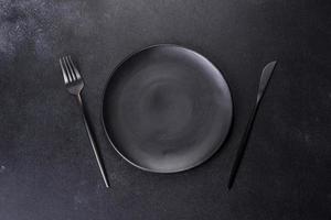 Black plate on a black background. Flat lay, top view, copy space photo