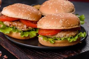 Three hamburger with beef meat burger and fresh vegetables on dark background photo