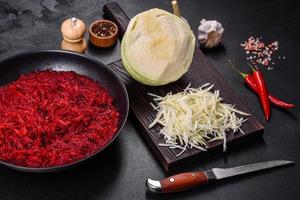 Chopped beetroot in a pan as well as spices and herbs on a wooden cutting board photo