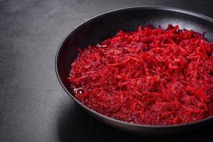 Chopped beetroot in a pan as well as spices and herbs on a wooden cutting board photo