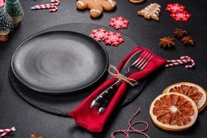 Christmas table setting with empty black ceramic plate, fir tree and black accessories photo