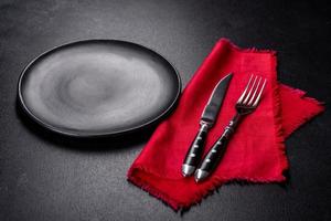 Christmas table setting with empty black ceramic plate, fir tree and black accessories photo