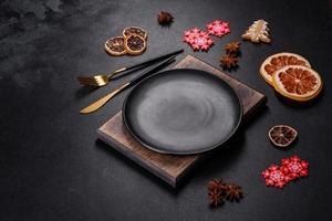 Christmas table setting with empty black ceramic plate, fir tree and black accessories photo
