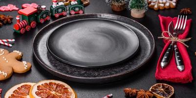Christmas table setting with empty black ceramic plate, fir tree and black accessories photo