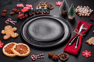 Christmas table setting with empty black ceramic plate, fir tree and black accessories photo