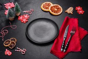 Christmas table setting with empty black ceramic plate, fir tree and black accessories photo