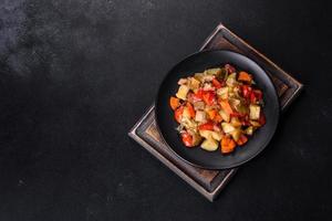 Vegetable stew or ratatouille with eggplant, tomatoes, sweet and hot peppers, onions, carrots and spices in plate photo
