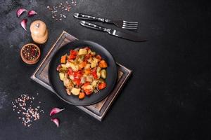 Vegetable stew or ratatouille with eggplant, tomatoes, sweet and hot peppers, onions, carrots and spices in plate photo