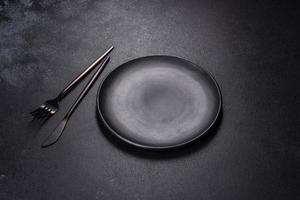 Black plate on a black background. Flat lay, top view, copy space photo