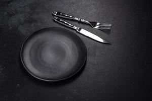 Black plate on a black background. Flat lay, top view, copy space photo