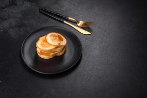 Delicious fresh pancakes on a black plate against a dark concrete background photo