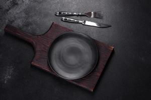 An empty plate with a knife, fork or spoon with a wooden cutting board photo