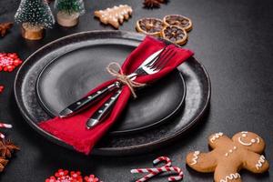 Christmas table setting with empty black ceramic plate, fir tree and black accessories photo