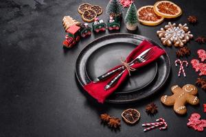 Christmas table setting with empty black ceramic plate, fir tree and black accessories photo