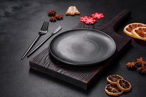 Christmas table setting with empty black ceramic plate, fir tree and black accessories photo