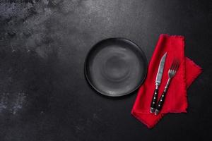 Christmas table setting with empty black ceramic plate, fir tree and black accessories photo